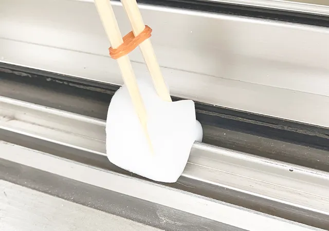 割り箸、輪ゴム、スポンジを合体させたアイテムで窓の枠掃除をする場面（撮影：grape編集部）