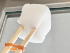 割り箸、輪ゴム、スポンジを合体させたアイテムで窓掃除をする場面（撮影：grape編集部）