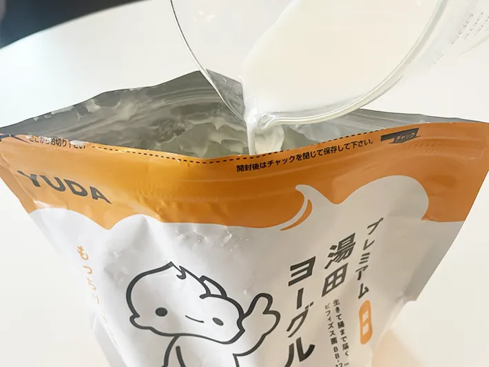 プレミアム湯田ヨーグルトに牛乳を入れる写真（撮影：grapeフード編集部）