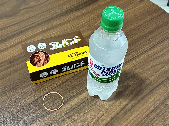 机に置かれた炭酸飲料と輪ゴムの写真（撮影：grapeライフハック編集部）