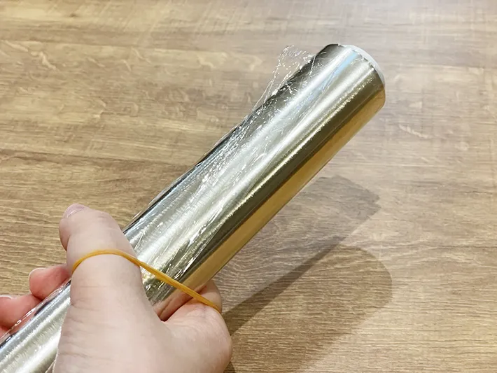 手に輪ゴムを引っかけてラップをひねり切り口を探している写真