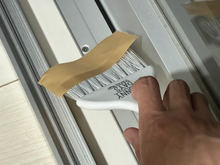 ミニほうきでサッシを掃除する場面の写真（撮影：grapeライフハック編集部）