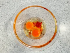 マヨネーズ、ラー油、七味唐辛子を入れて、卵を割り入れた場面（撮影：grapeフード編集部）