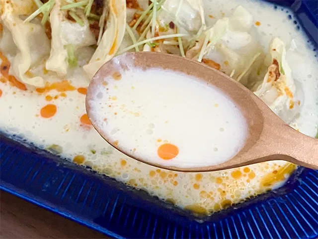 『豆乳ラー油餃子』のスープを味わう場面（撮影：grapeフード編集部）