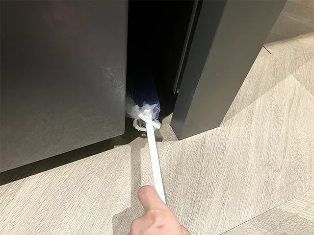 水切りネットを被せたモップで隙間を掃除する場面（撮影：grapeライフハック編集部）