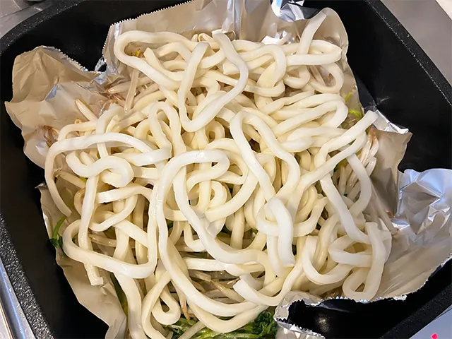 モヤシと豆苗、うどんをフライパンで炒める場面（撮影：grapeフード編集部）