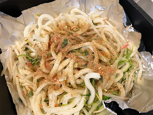モヤシと豆苗、うどんをフライパンで炒め、五目チャーハンの素をかけた場面（撮影：grapeフード編集部）