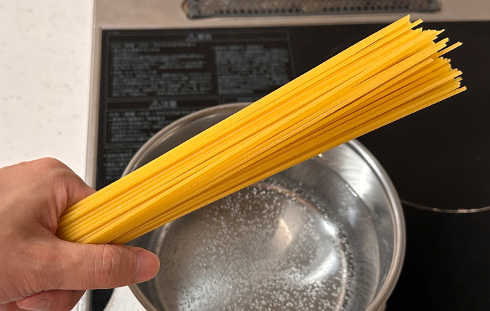 非結束タイプのスパゲッティの束を掴んでいる写真
