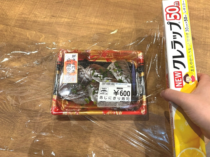 寿司パックをラップで包む（撮影：grapeフード編集部）