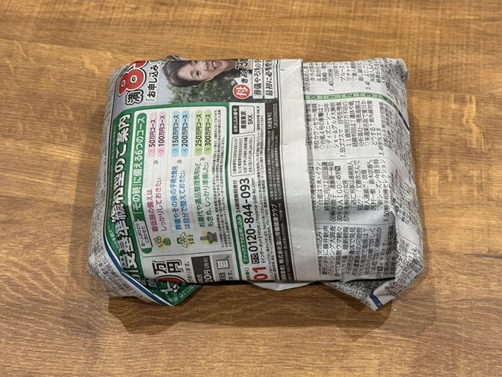 寿司パックを新聞紙で包む（撮影：grapeフード編集部）