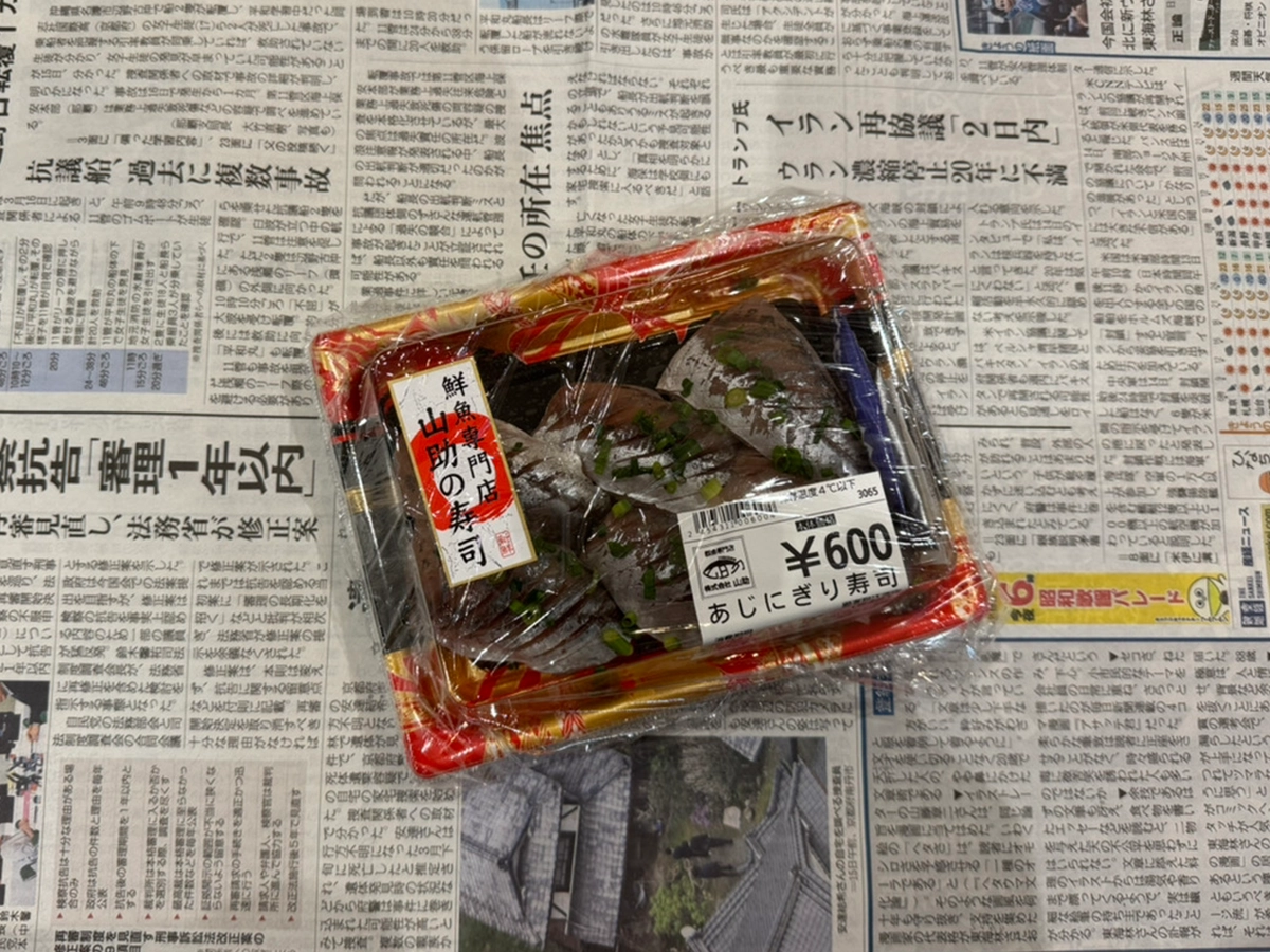 寿司パックを新聞紙で包む（撮影：grapeフード編集部）