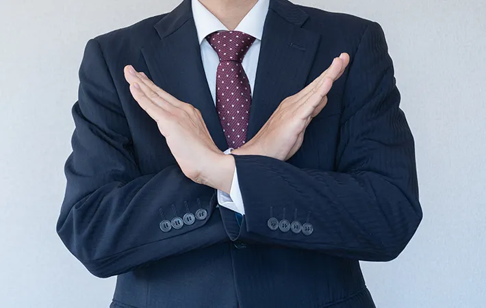 手で『ダメ』の意思表示をする男性の写真