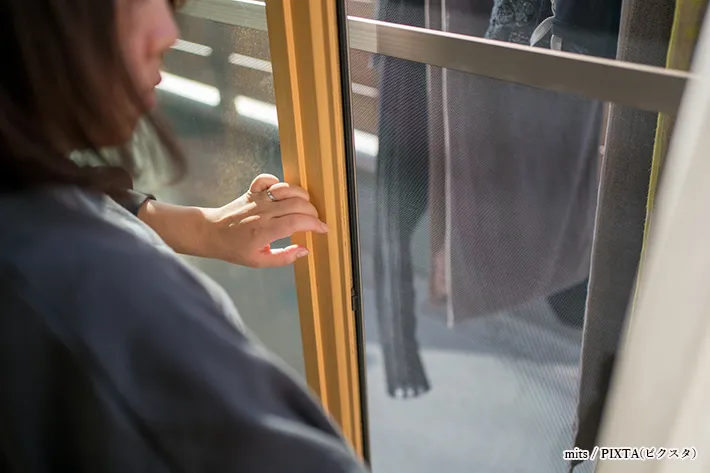 マンションの窓を開ける女性