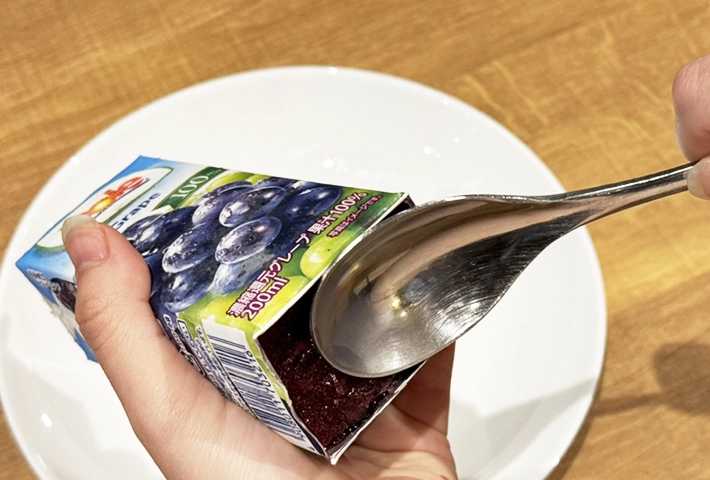 紙パックジュースアイスを取り出すときはスプーンで押す（撮影：grapeフード編集部）