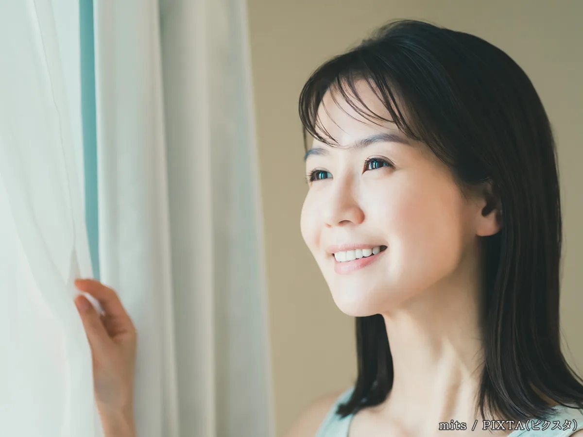 窓を開ける女性の写真
