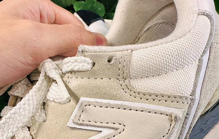 ニューバランスのスニーカーを持ち上げて『穴』に注目している写真