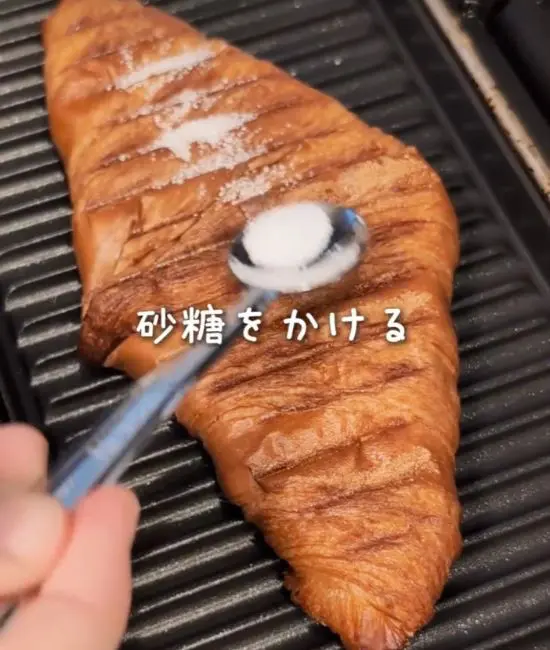 クロワッサンに砂糖を振りかけている様子