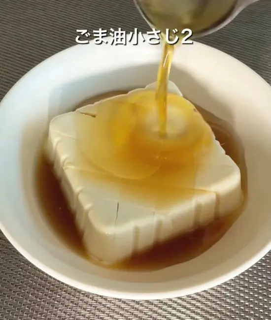 豆腐に麺つゆとごま油を回しかけている様子