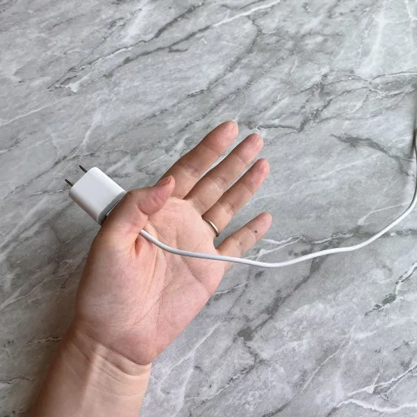 親指と人差し指で電源アダプターを挟んでいる様子（撮影：grapeライフハック編集部）