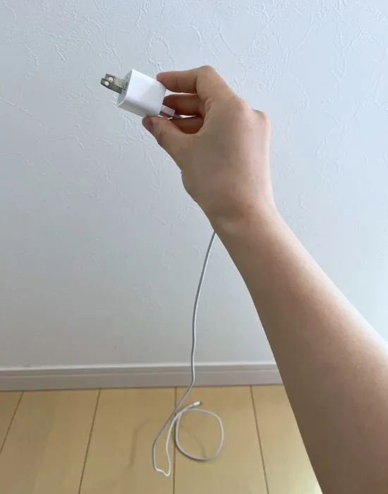 電源アダプターを持ち上げてケーブルをほどいている様子（撮影：grapeライフハック編集部）