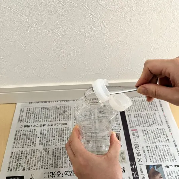 幅広のスプーンで油の容器のキャップを外している様子（撮影：grapeライフハック編集部）