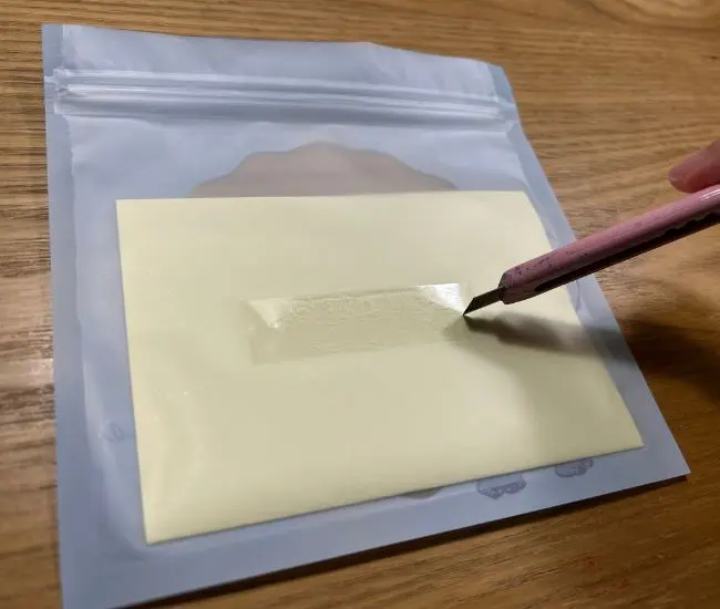 チャックつき保存袋にカッターで切り込みを入れている様子（撮影：grapeライフハック編集部）