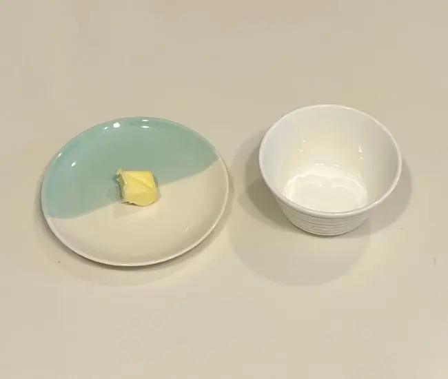お皿にのせたバターと小さめのカップ（撮影：grapeフード編集部）