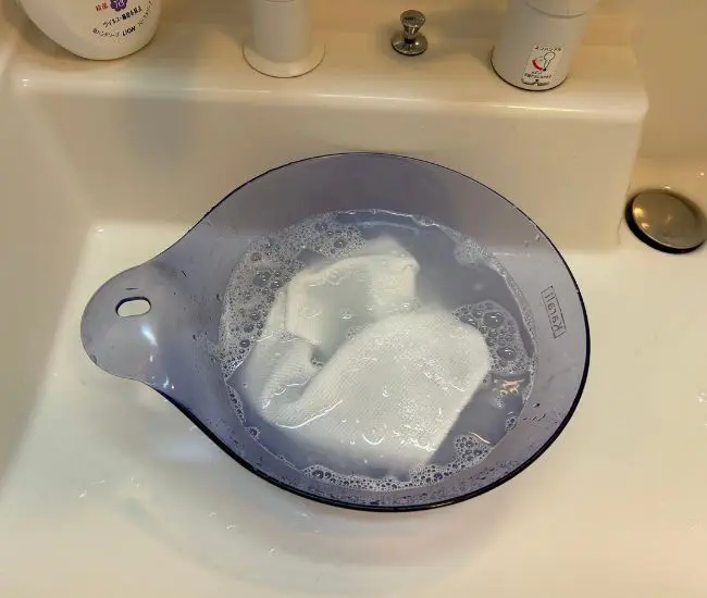 クロスを石けん水に浸して絞る様子（撮影：grapeライフハック編集部）