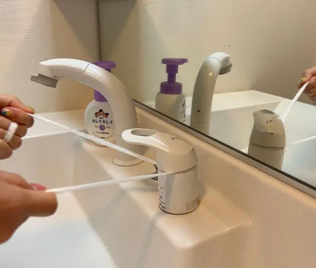 蛇口の隙間をビニール紐で擦る様子（撮影：grapeライフハック編集部）