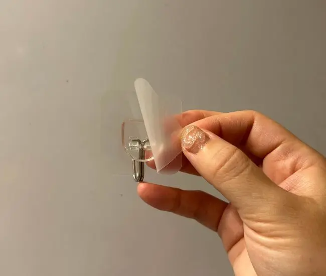 フックを冷蔵庫横に貼りつける様子（撮影：grapeライフハック編集部）