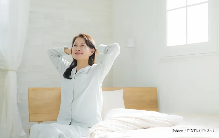 『ベッドでストレッチするシニア女性』の写真