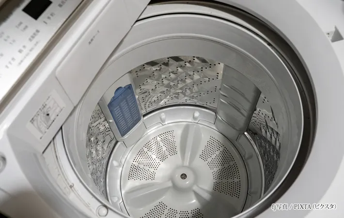 『少し汚い縦型洗濯機の洗濯槽』の写真