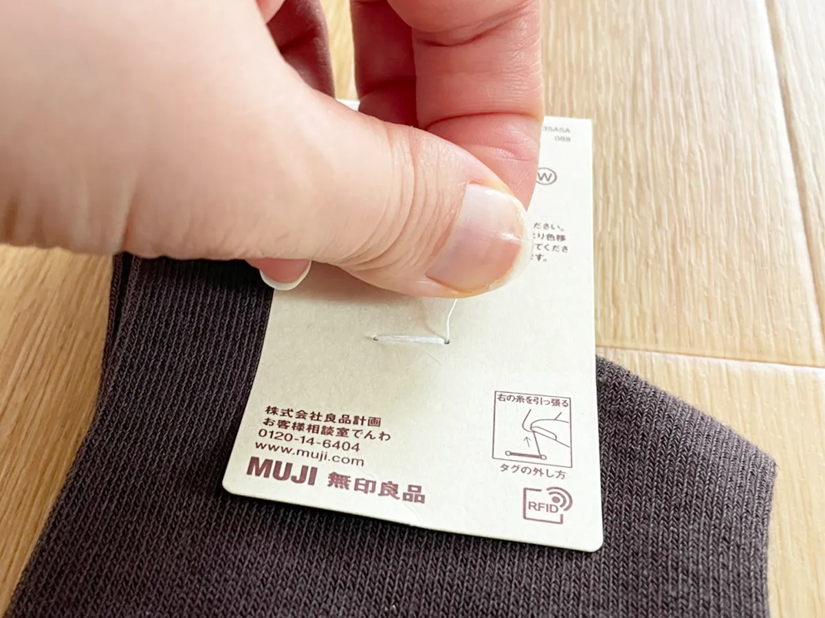 無印良品の靴下のタグ糸を持つ写真（撮影：grapeライフハック編集部）