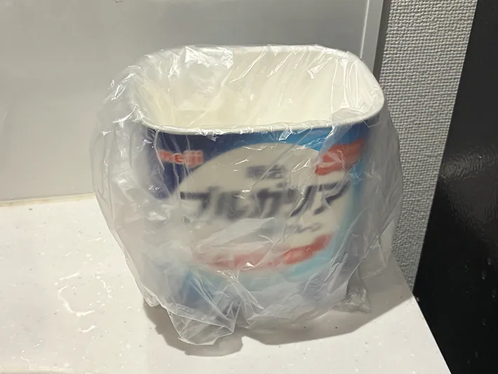 ビニール袋をかぶせた明治ブルガリアヨーグルトの空き容器（撮影：grapeライフハック編集部）