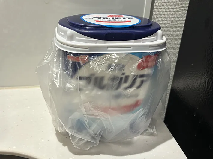 ビニール袋をかぶせて蓋を閉めた明治ブルガリアヨーグルトの空き容器（撮影：grapeライフハック編集部）