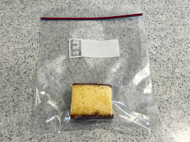 ラップに巻いたカステラをジッパー付き袋に入れた場面（撮影：grapeフード編集部）