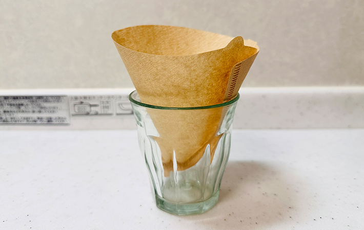 紙のコーヒーフィルターをコップにセットしている写真