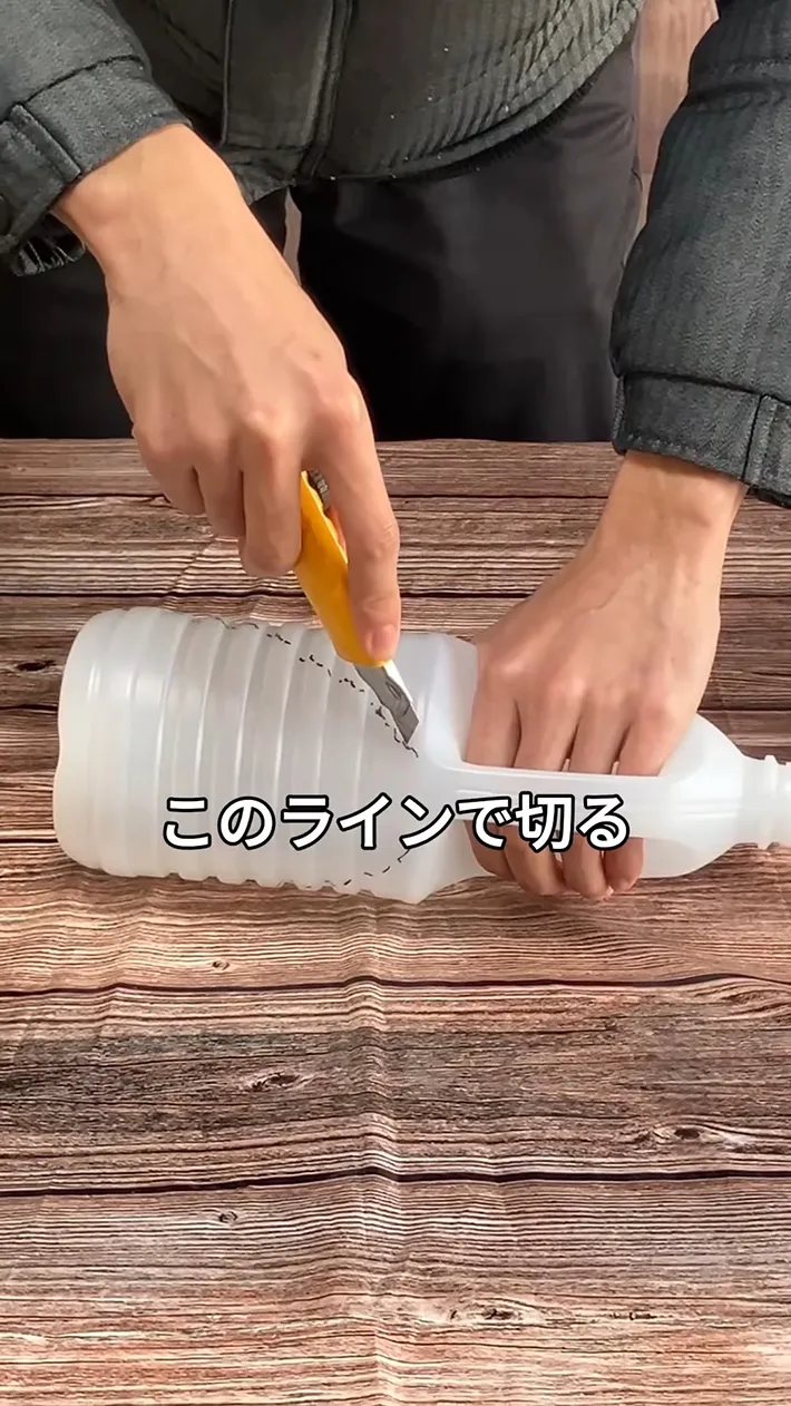 カッターでサラダ油容器に切れ込みを入れる場面