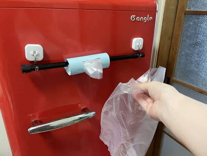 冷蔵庫にトイレットペーパーの芯で作ったビニール袋の収納を取り付けた写真（撮影：grapeライフハック編集部）