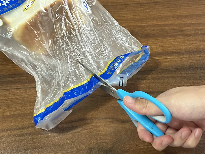 食パンの袋にハサミで切れ込みを入れる場面（撮影：grapeライフハック編集部）
