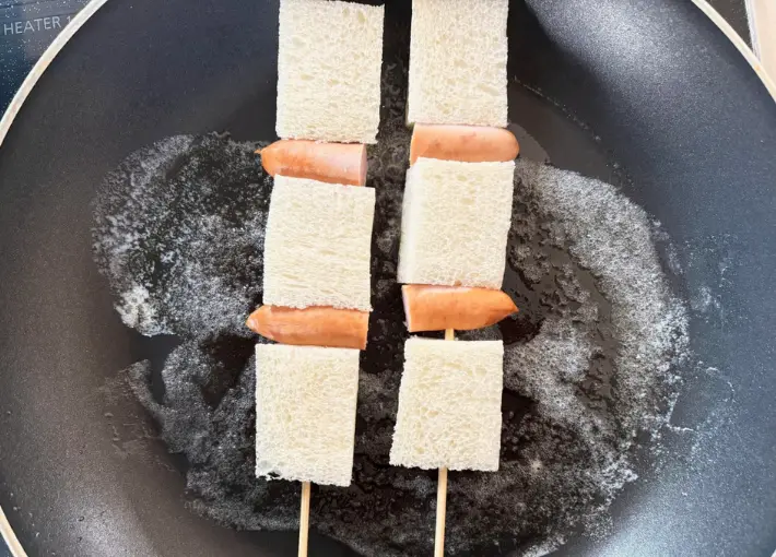 フライパンに竹串に食パンとウインナーを刺したものを並べた画像（撮影：エニママ）