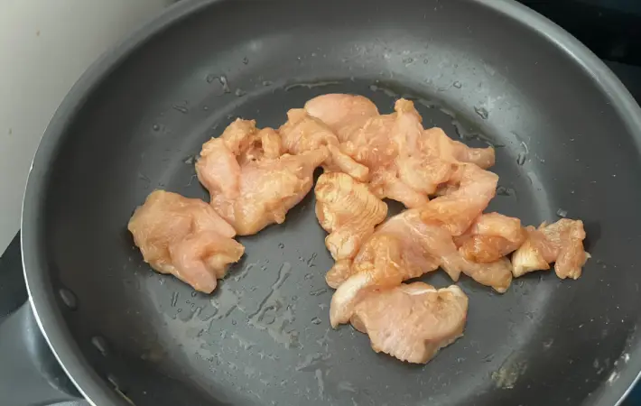 フライパンにごま油を引き、鶏むね肉を炒めている画像（撮影：エニママ）