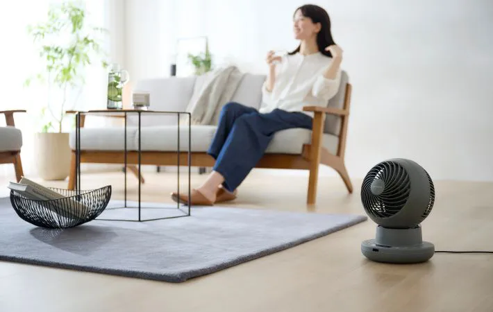 ソファに座る女性とサーキュレーターの写真