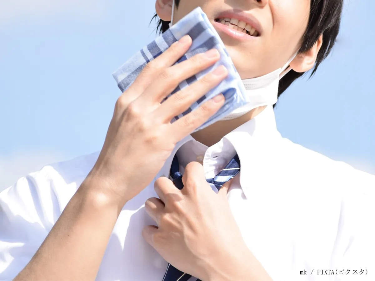 汗をぬぐう男性のイメージ画像