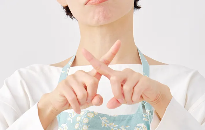手でバツを作る女性