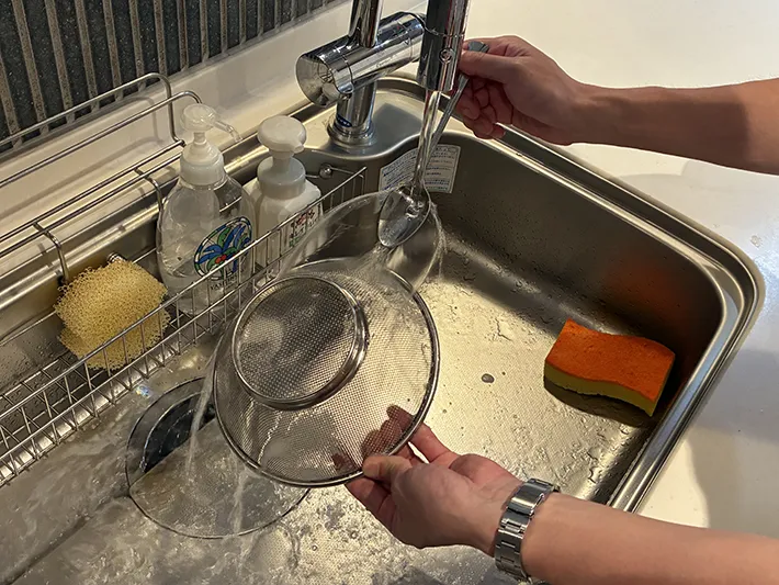 スプーンに水を当ててザルを洗う場面（撮影：grapeライフハック編集部）