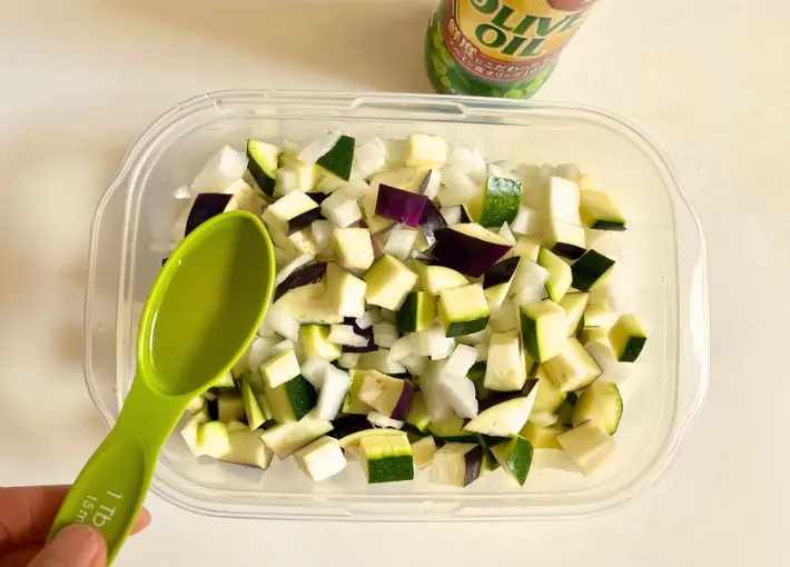 カットした野菜にオリーブオイルを加える（撮影：エニママ）