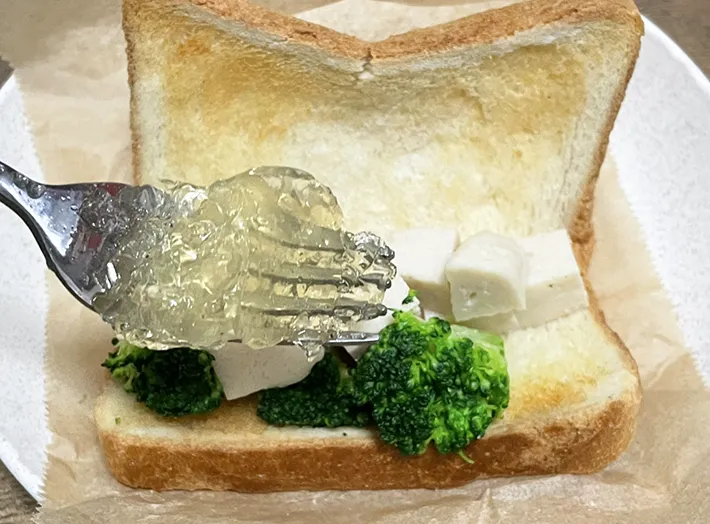 コンソメゼリーをサンドイッチにかける写真（撮影：grapeフード編集部）