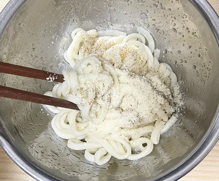 うどん、塩、コショウ、粉チーズを加えて混ぜる写真（撮影：grapeフード編集部）