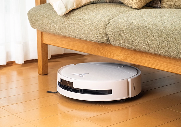 ロボット掃除機『DEEBOT T80S OMNI』がソファの下に入り込んで掃除をしている写真